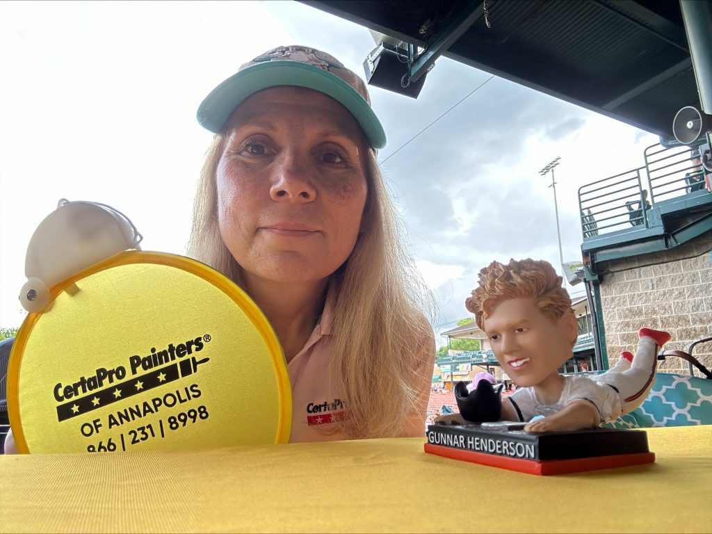 Monica ingson with certapro hand fan and gunnar henderson bobblehead