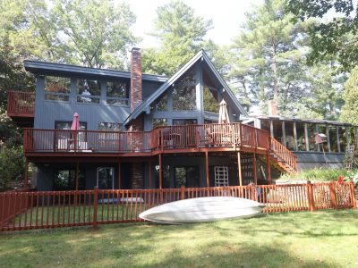 lake house with blue-grey siding and red deck railing