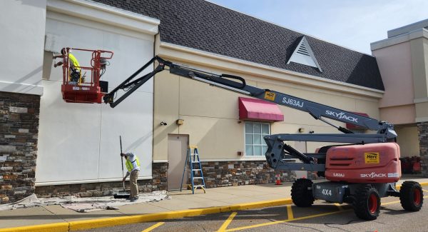 person on boom lift painting retail exterior