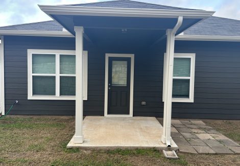 covered rear doorway of house with charcoal painted siding
