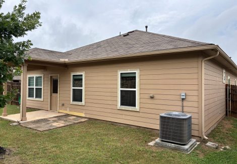back of house with tan siding and AC compressor unit outside