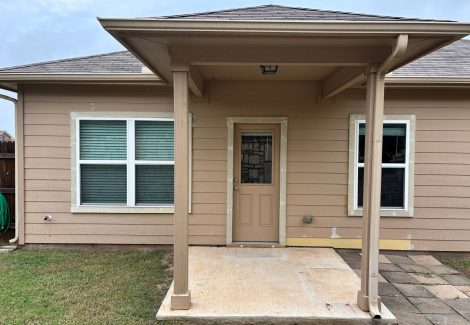 back door of tan house with small covered patio