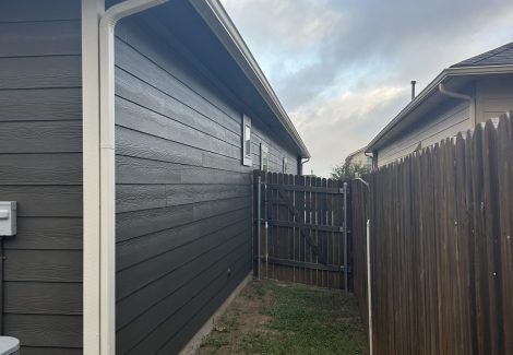 side of house with charcoal painted siding and wooden fence
