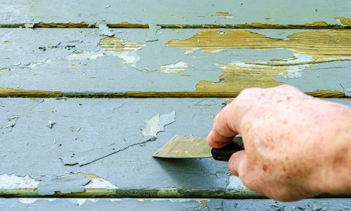 Man's,Hand,Shown,Scraping,Old,Gray,Paint,From,Wood,Porch