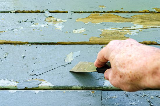 Man's,Hand,Shown,Scraping,Old,Gray,Paint,From,Wood,Porch