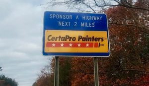 Blue sponsor a highway sign with CertaPro logo on it.