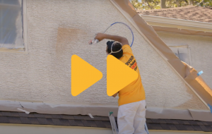 Photo of a person spraying a house that is clickable to a YouTube video of them spraying a house