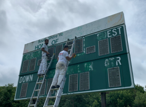 Painters on ladders painting scoreboard