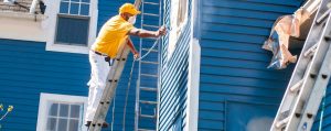 painter spraying paint on an exterior of a home.