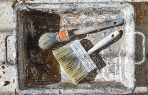 Two old paint brushes inside an old paint tray