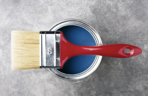 Paint can with historic blue color inside and paintbrush with red handle on top