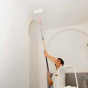 CertaPro Painter in white shirt painting a high ceiling with a roller