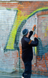 CertaPro Painters Worker washing graffiti with a power washer