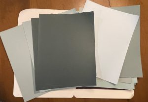 A folder of large paint chips in blues and greens