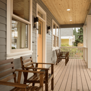 Covered porch of a home with a chairs and a yellow front door