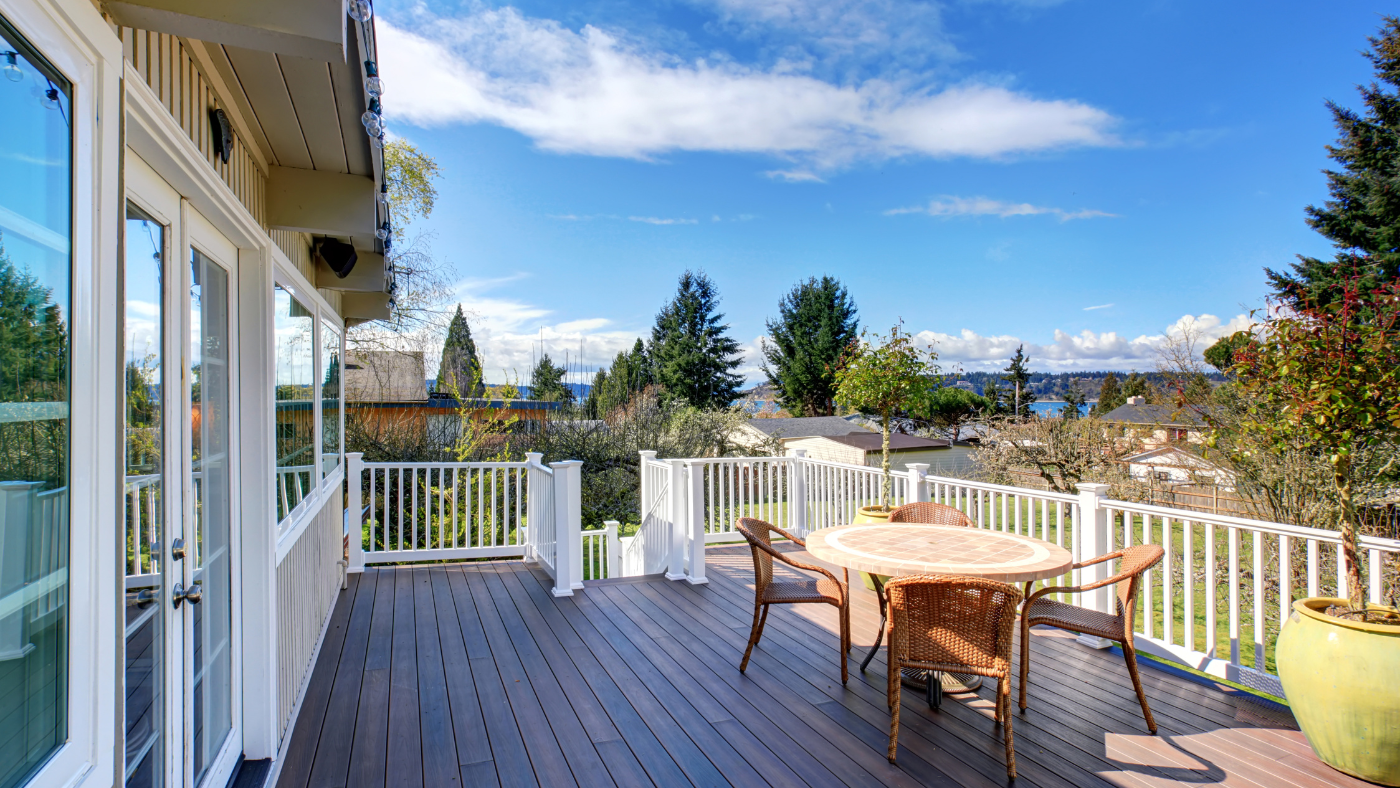 Dark stained deck overlooking trees and ocean in far background