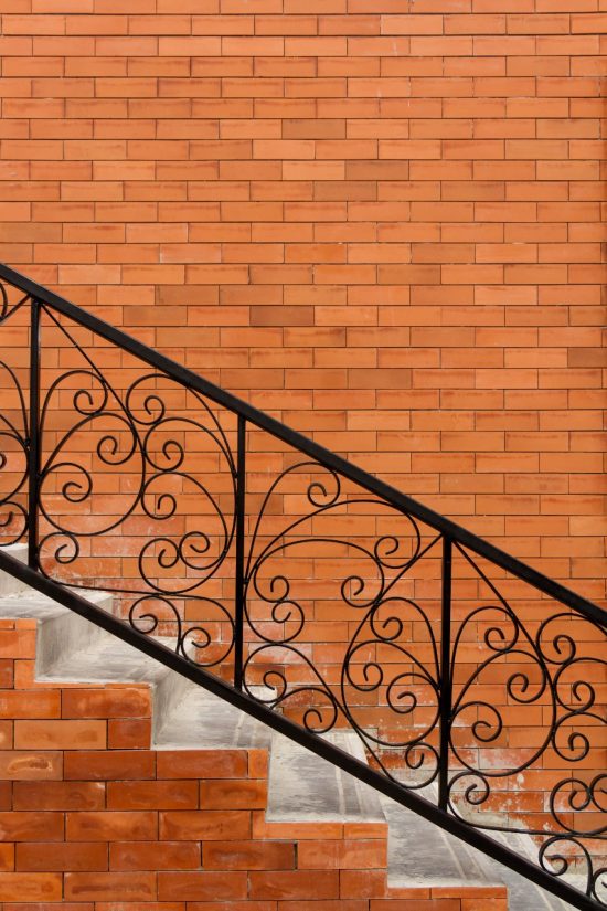 decorative iron railing on stairway with brick wall background