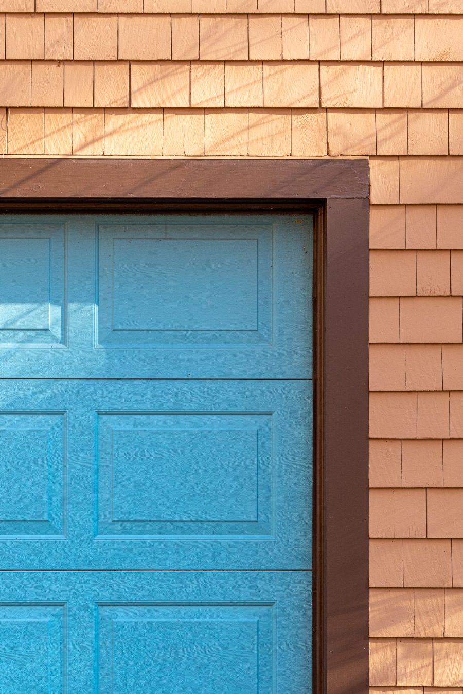 Garage door trim painted with brown paint against tan shingles. Preview Image 5