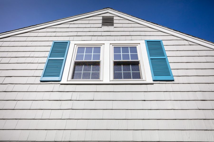 Side of home with gray painted cedar shingles and teal window shutters Preview Image 6