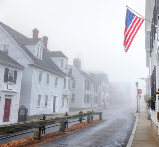 Homes in Plymouth Massachusetts in the fog with a flag in the foreground
