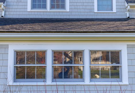 View of dormer windows and gray stained cedar shingles on home in Duxbury, MA
