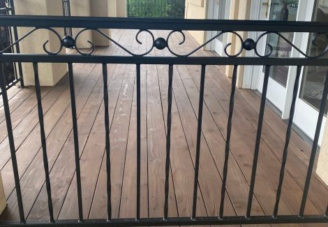 stained wooden deck with black metal railing