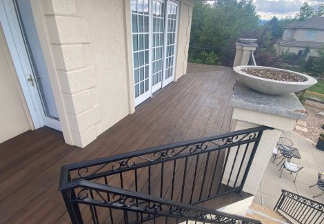 stained wooden deck against house with black metal railing