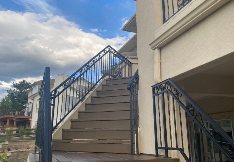 stained wooden deck staircase with black metal railing