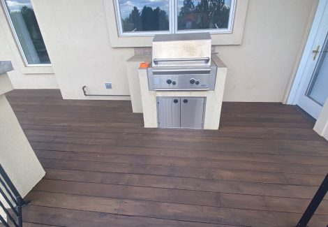 propane grill on stained wooden deck