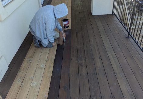 painter stripping old stain from wooden deck