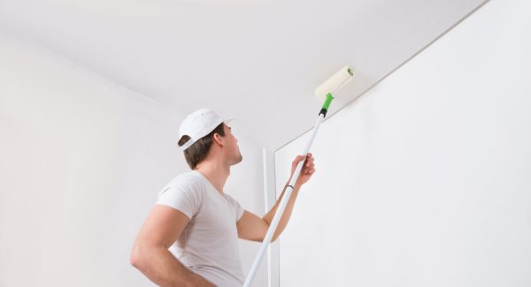 man painting interior ceiling with roller brush