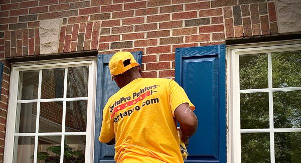 Man in Gold Shirt Painting Shutters
