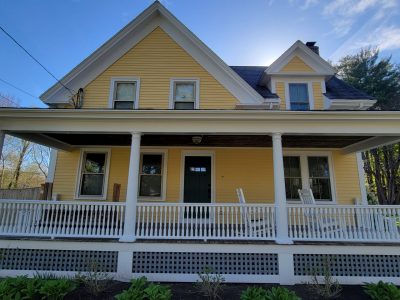 Yellow house with front porch and white railings
