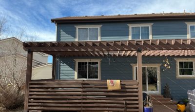 blue house with stained wooden pergola and fence