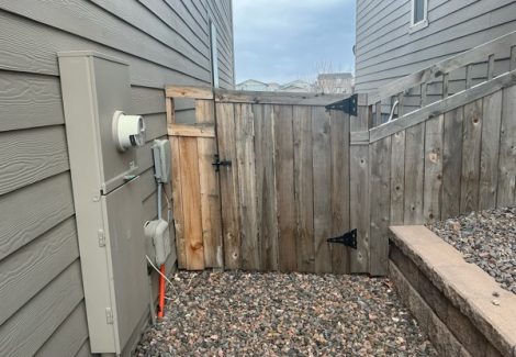 worn wooden fence gate against house