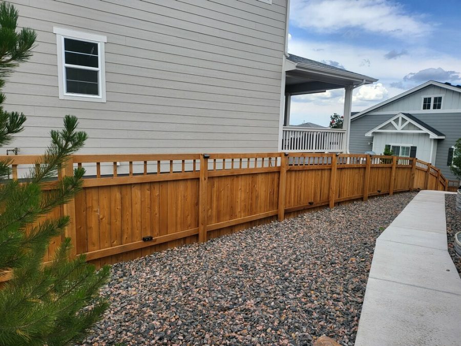 gravel landsaping and stained wooden fence surrounding home
