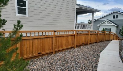 gravel landsaping and stained wooden fence surrounding home