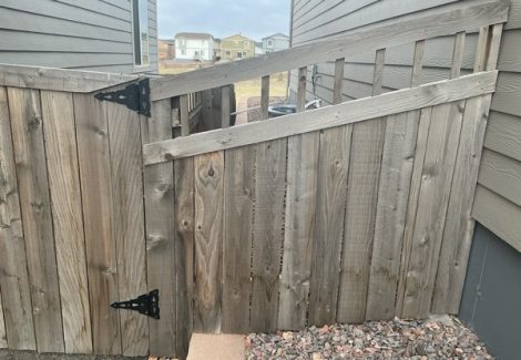 worn wooden fence gate against house