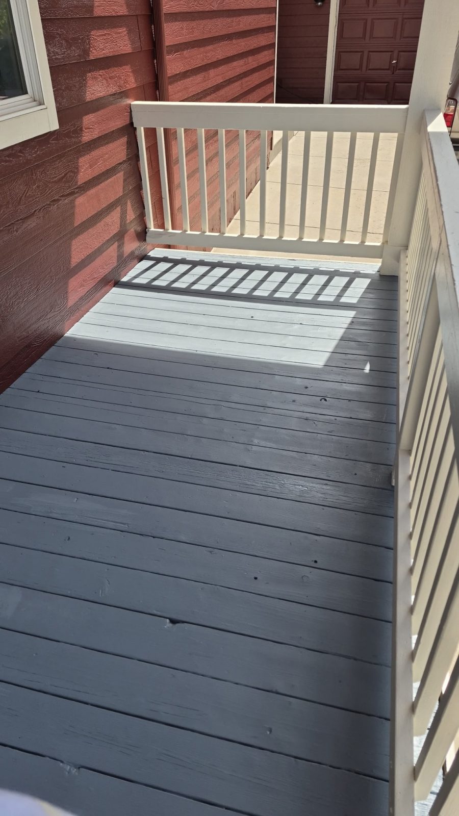 attached wooden porch painted grey with white rail against dark red siding Preview Image 4