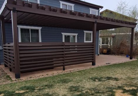 blue house with stained wooden pergola and fence