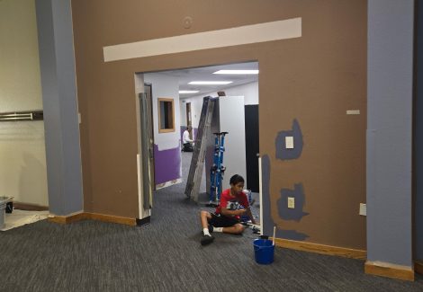 man sitting in hallway painting wall