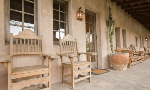 Old wooden chairs on a ranch house covered porch.