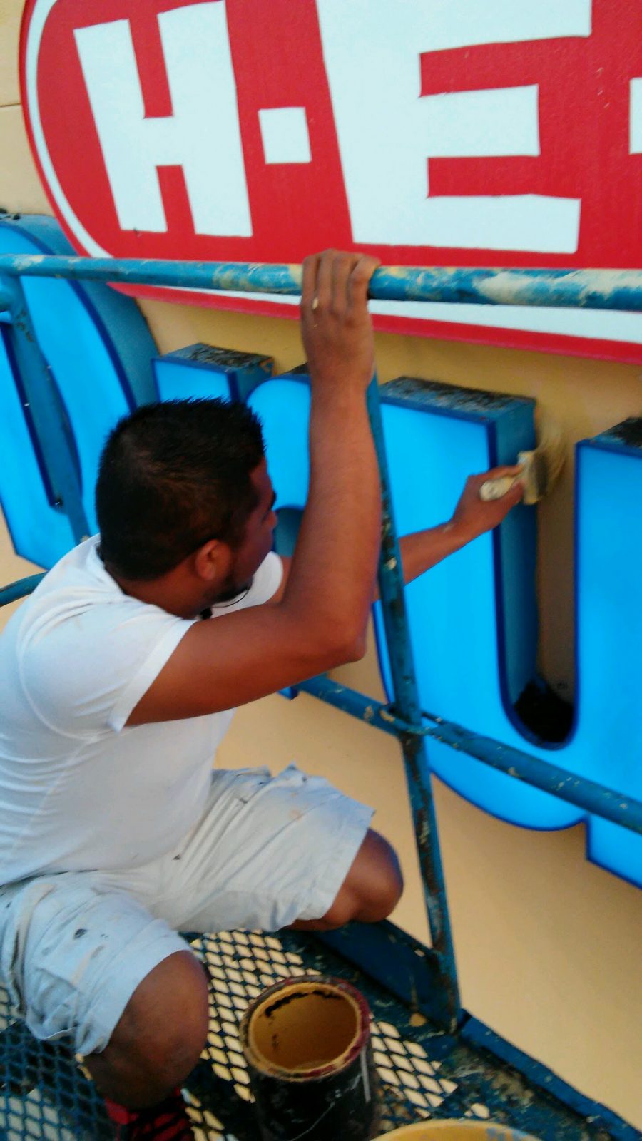 painter brushing paint around sign on storefront Preview Image 13