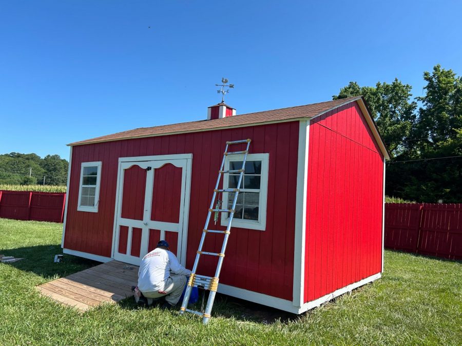 ladder against red shed being painted by painter