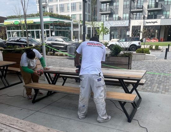 painters sanding wooden picnic tables