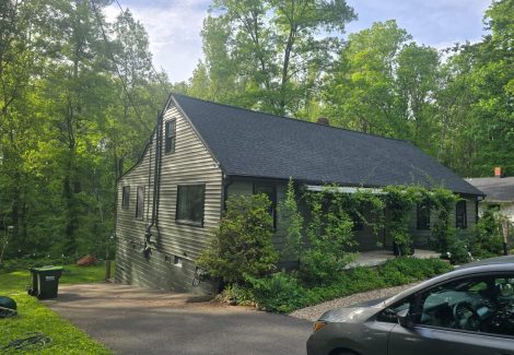front corner view of driveway, and house with painted siding and brick