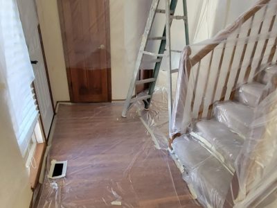 staircase and foyer covered in plastic sheeting for painting