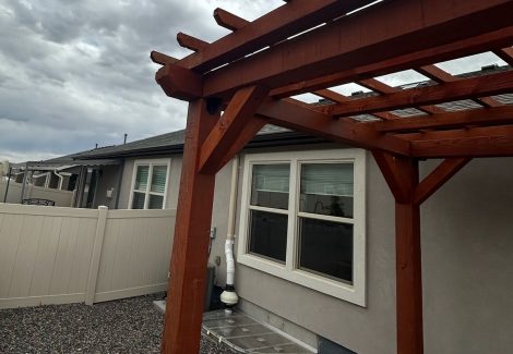 stained wooden pergola behind home