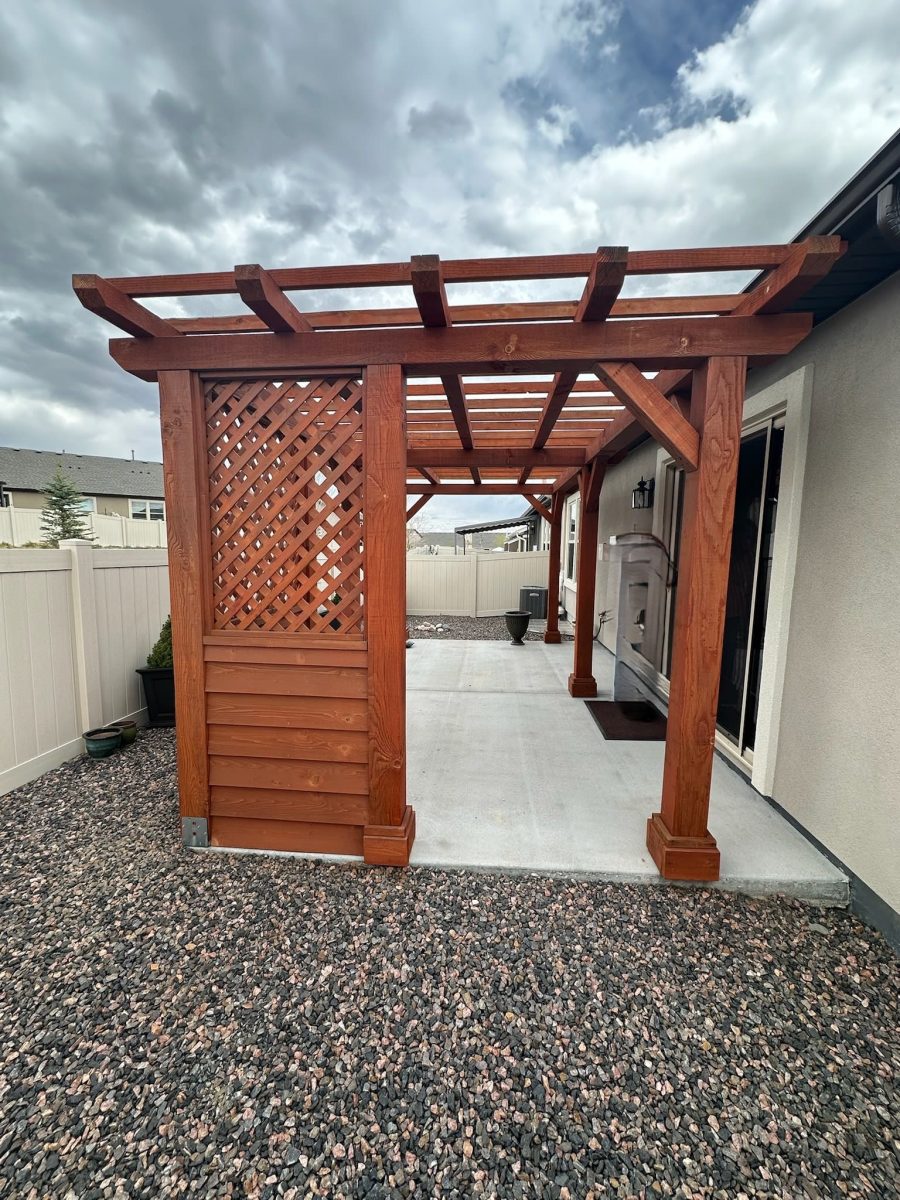 stained wooden pergola behind home