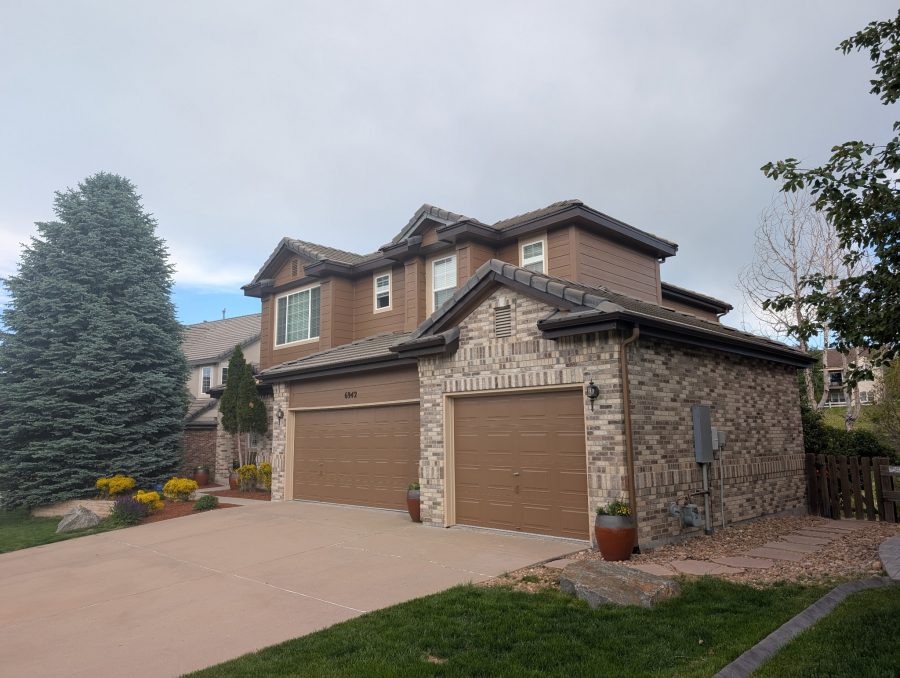 house exterior with brick and brown painted siding and garage doors